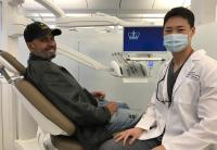 a dentist in a white coat sitting next to patient in a dental exam chair